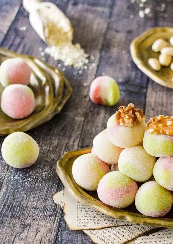 Boules d’amandes tricolores roulées dans le sucre et décorées de noix