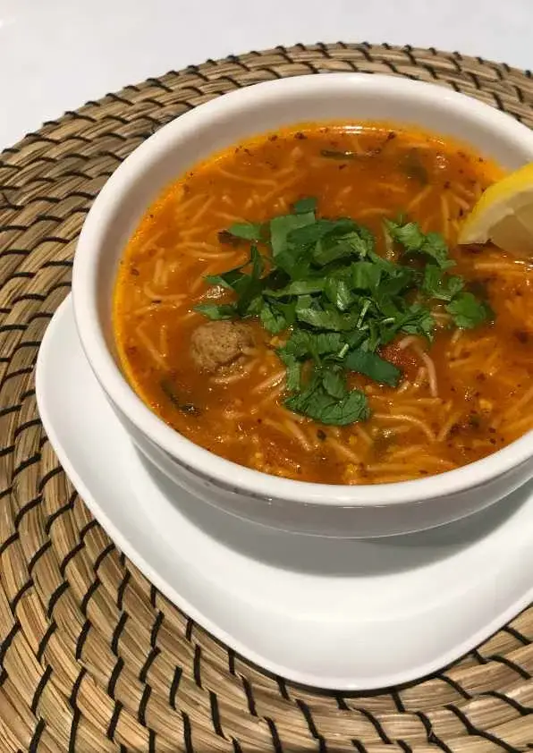 Bol de chorba aux vermicelles et boulettes de kefta garni de coriandre fraîche et citron