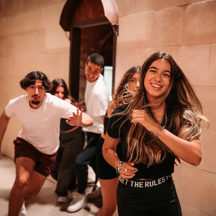 Groupe de jeunes adultes qui court en riant dans un couloir de pierre chez Fort Boyard Aventures Lyon