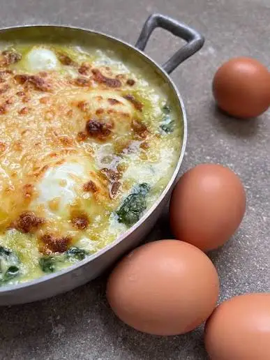 Gratin d'épinards aux œufs mollets et béchamel gratinée, servi dans un poêlon