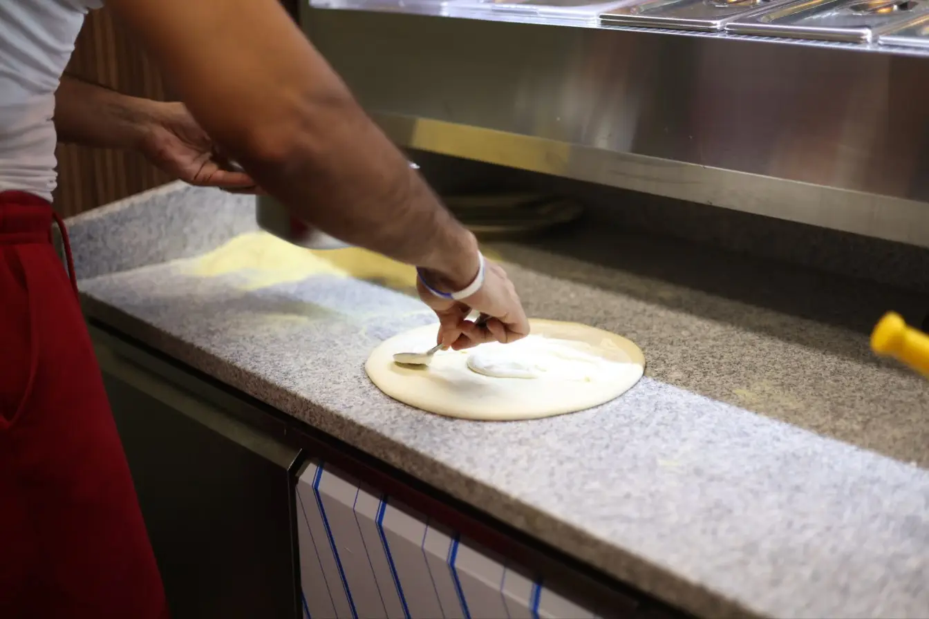 Le pizzaiolo de Vittoria garnit une pâte à pizza levée lentement, à Corbas